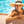 vrouw hangt met armen over elkaar in schitterend zwembad over stenen rand met rieten hoed